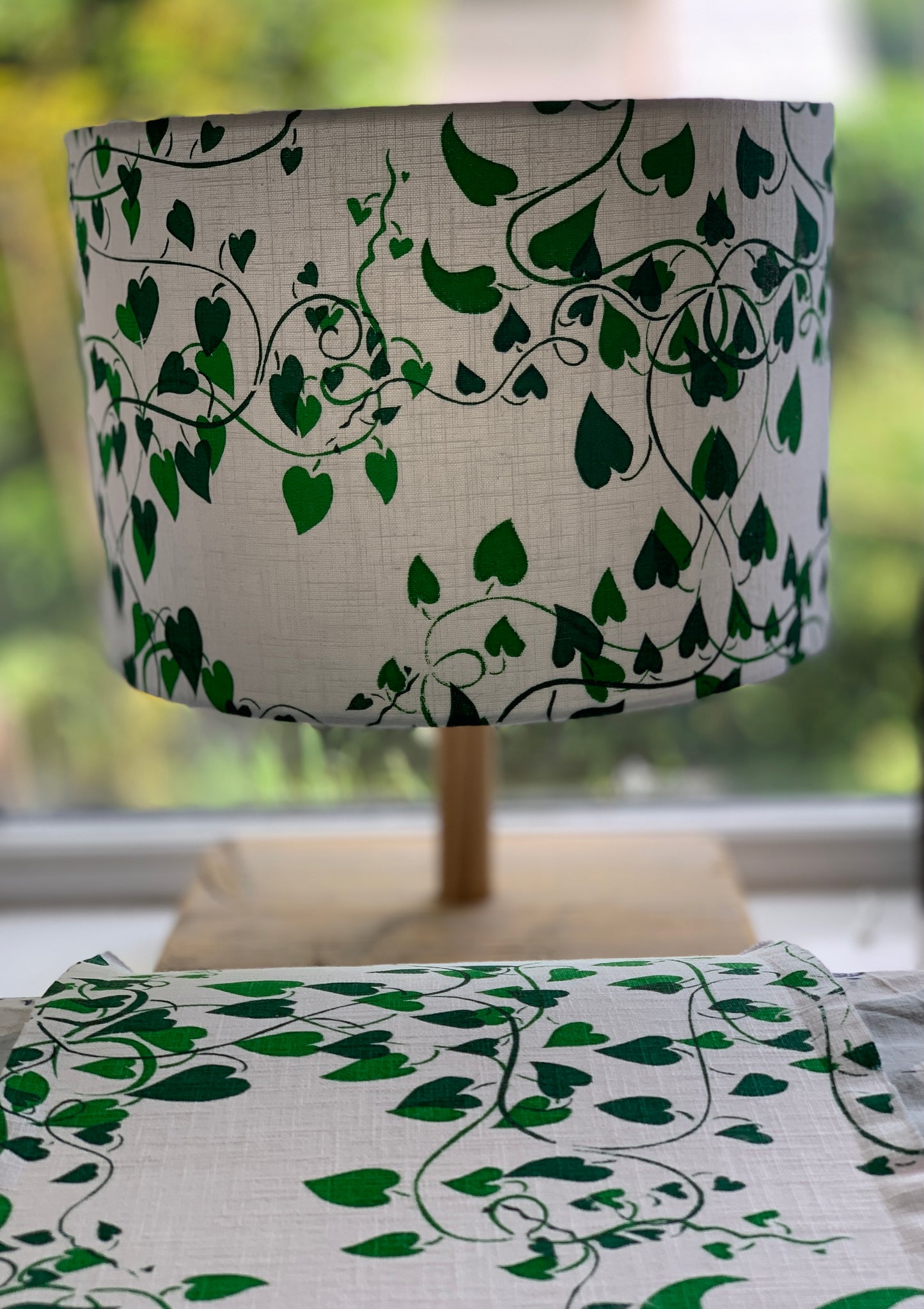Table lampshade with a white linen background and two shades of green convolvulus vines running over it.
