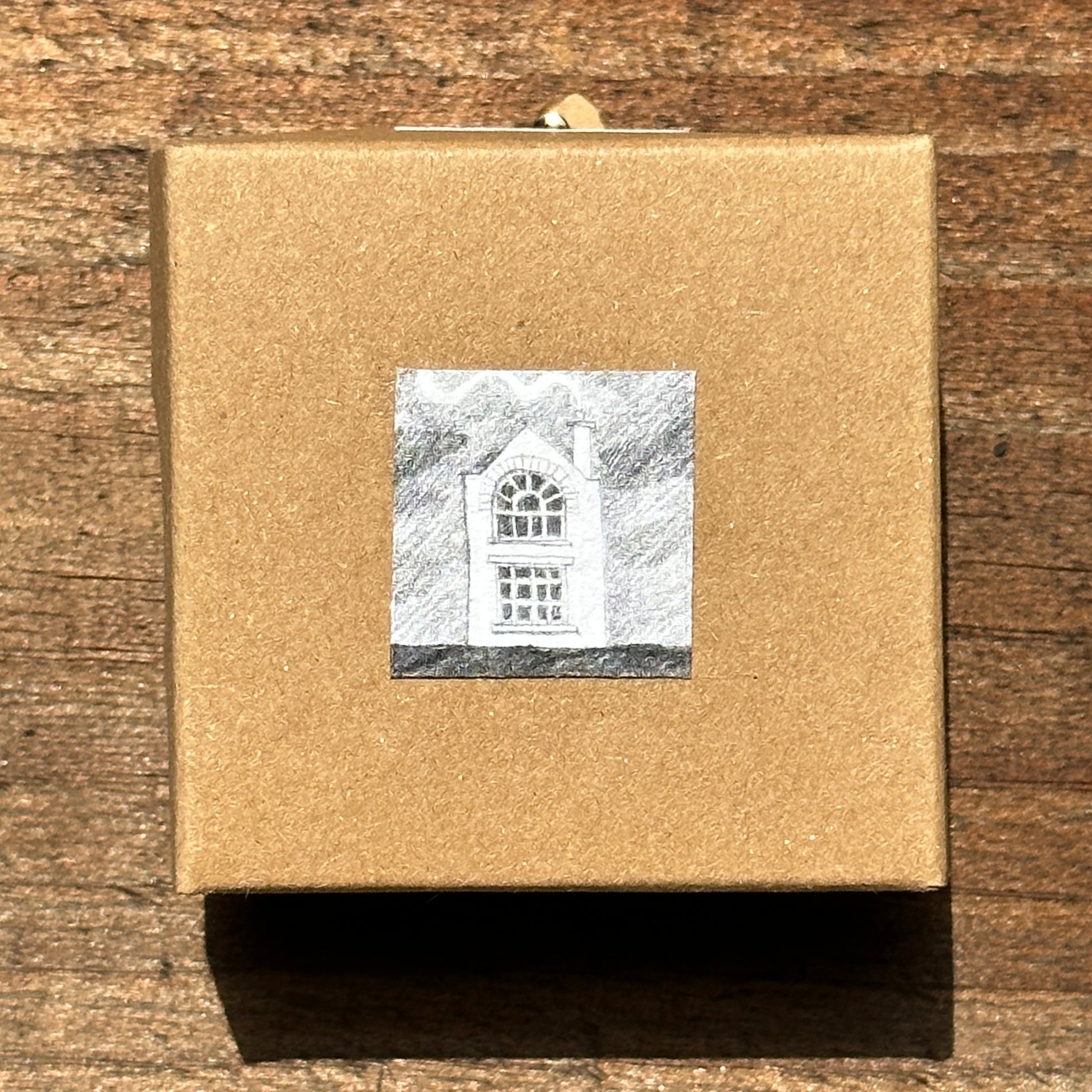 Front of display box for miniature handmade paper house on plywood base.