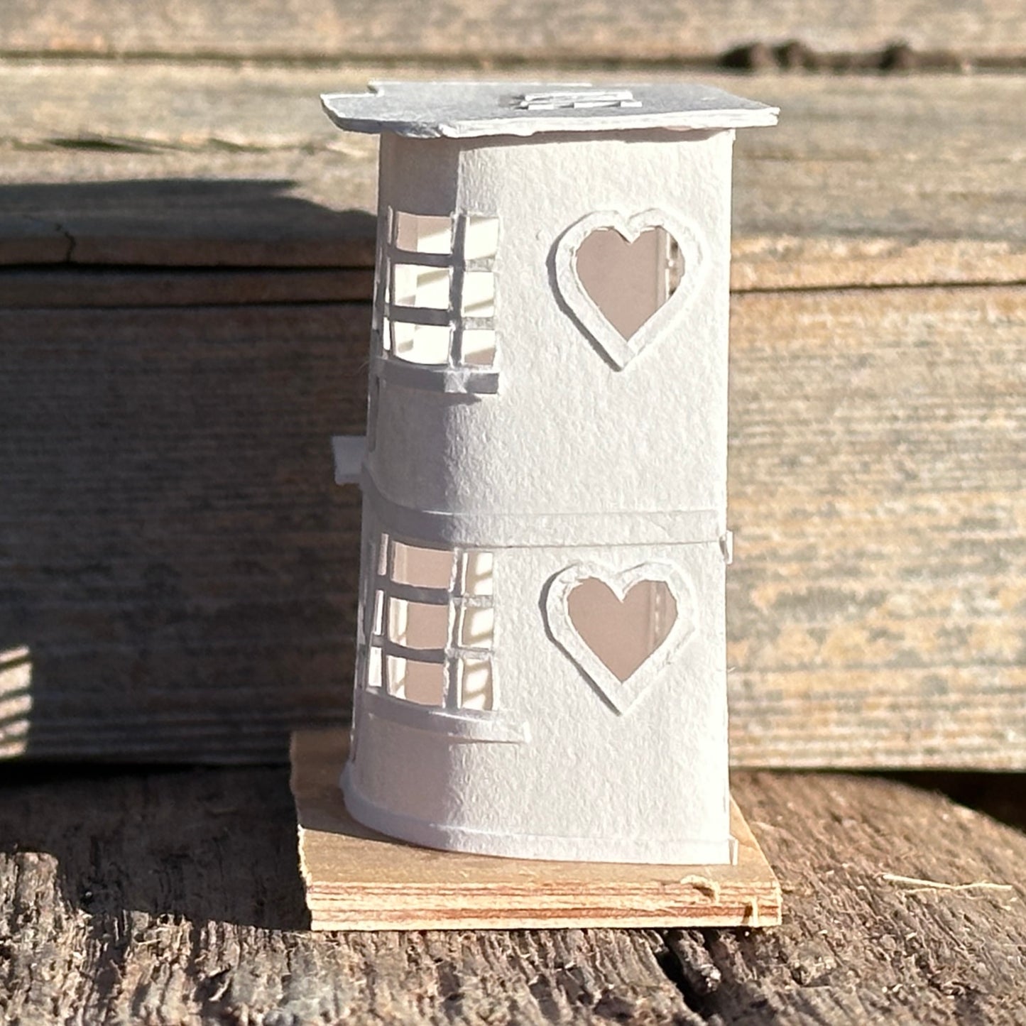 Modern House front elevation of white paper modernist style house with cut-out hearts on plywood base
