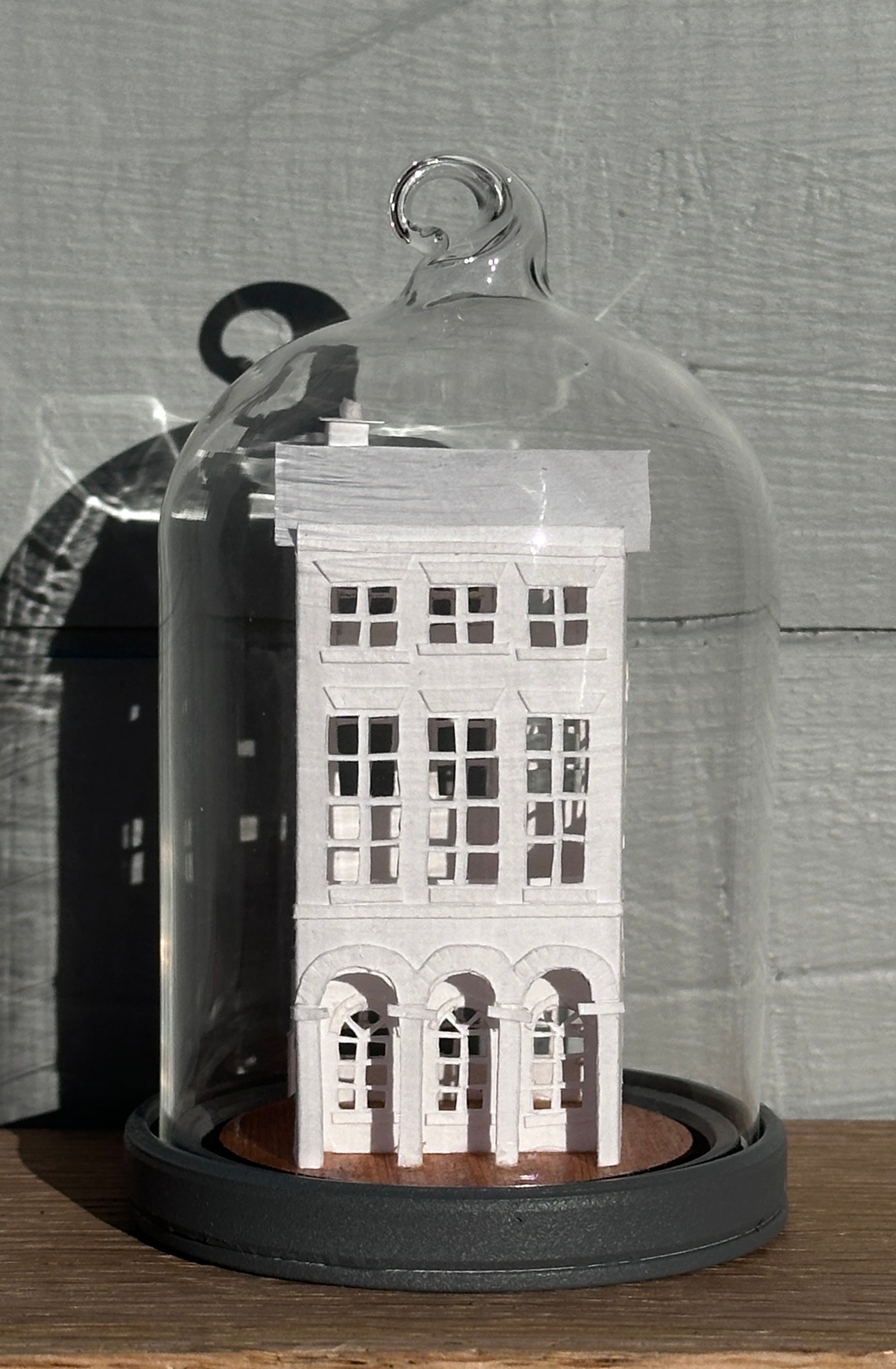 three storey paper house with triple arched colonnade on grey painted base  in glass dome