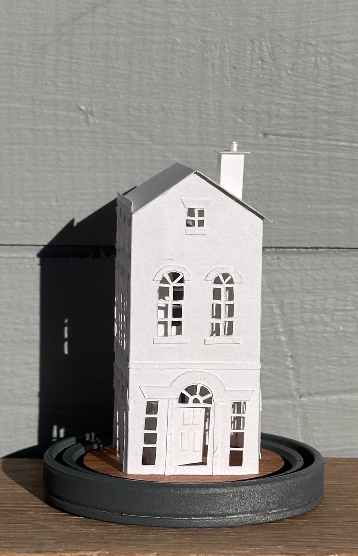 three storey paper house with triple arched colonnade on grey painted base  side elevation with front door and arched fanlight 