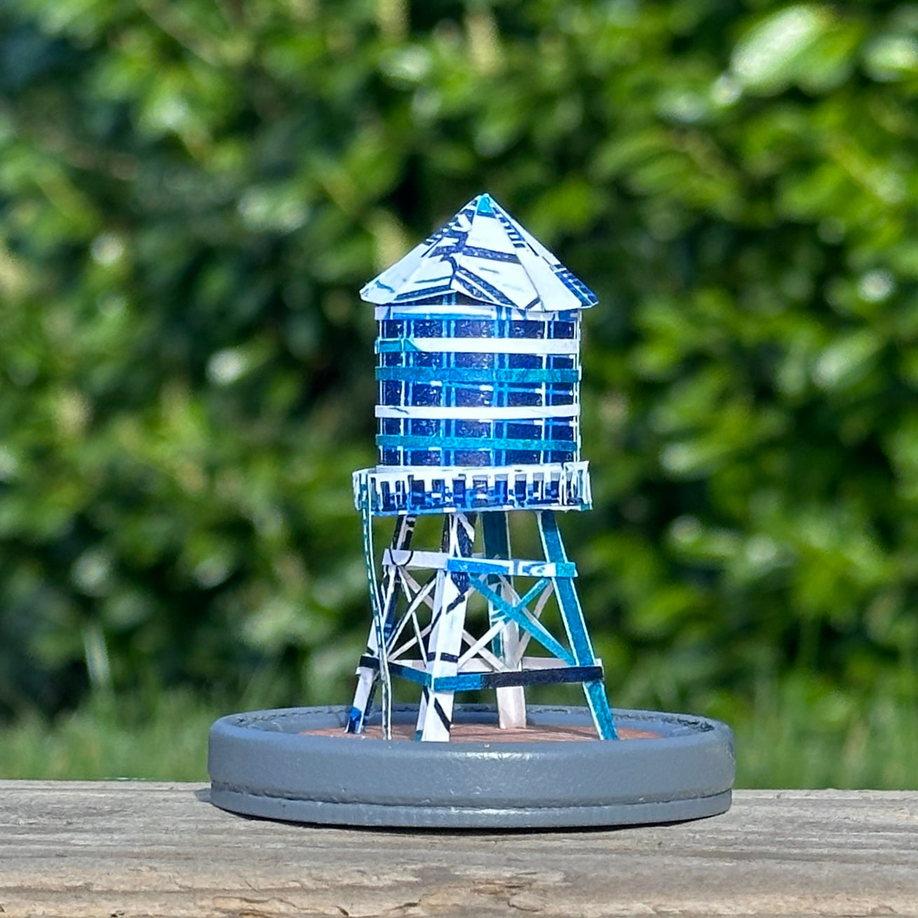 Handcut paper water tower over printed in shades of blue on grey base