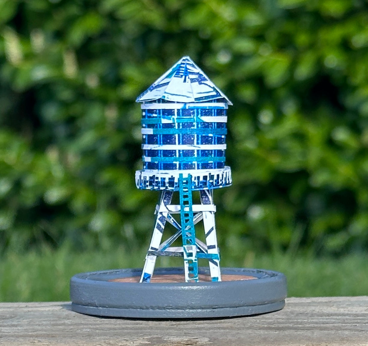 Handcut paper water tower over printed in shades of blue on grey base