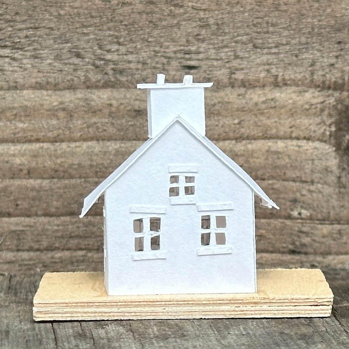 white paper gable fronted house with double chimney on plywood base
