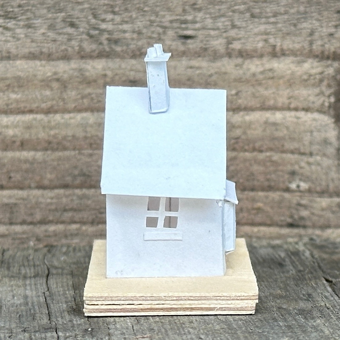 white paper gable fronted house with double chimney on plywood base