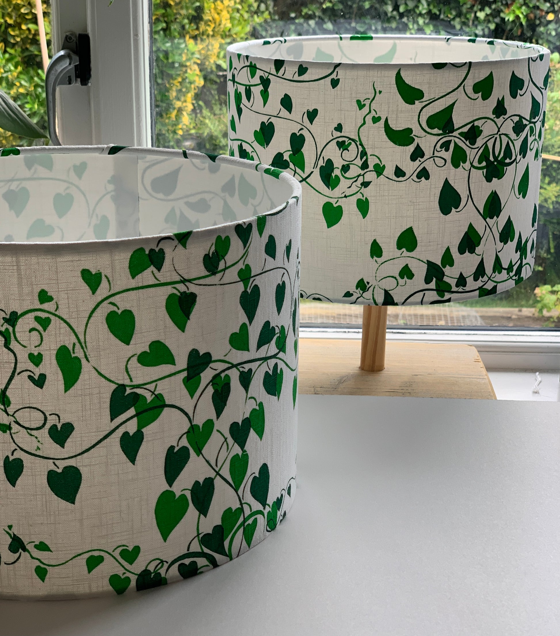  Two shades of green on white fabric  handprinted lampshades in  a convolvulus design.