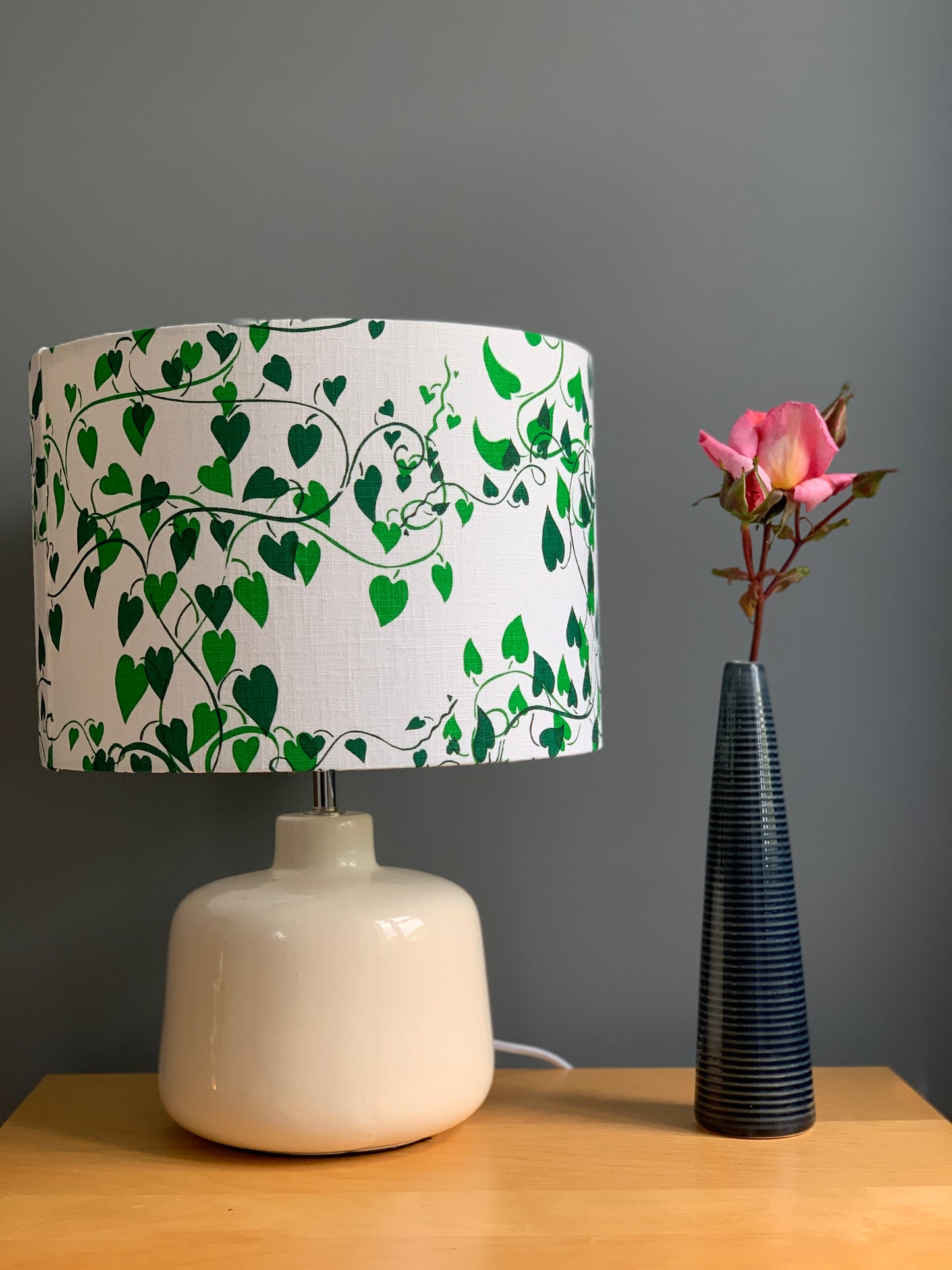 Shades of green on white fabric  handprinted lampshade in  a convolvulus design on cream lamp base.