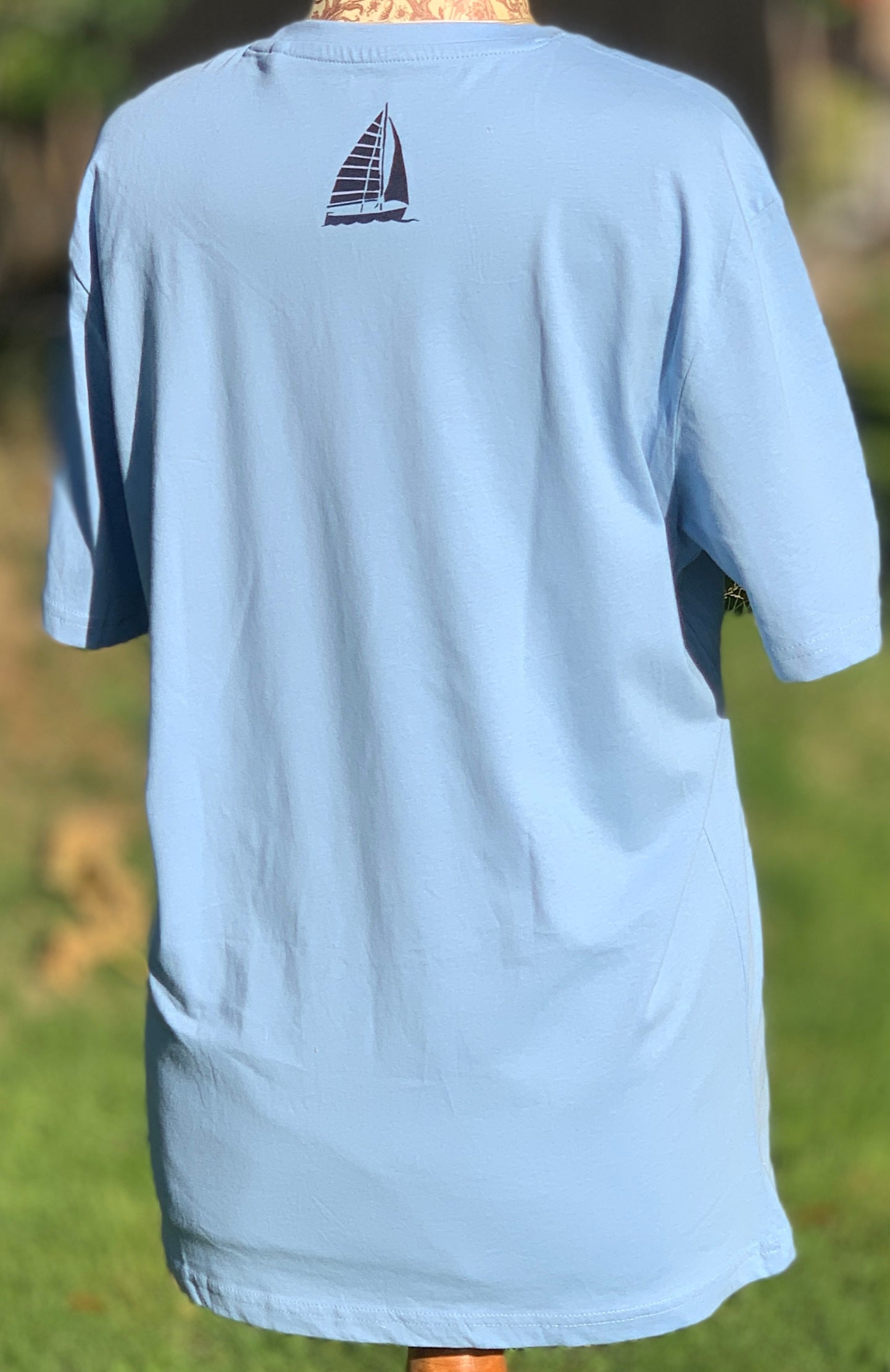 Back of pale blue T-shirt with turquoise blue design  of boat at neck.
