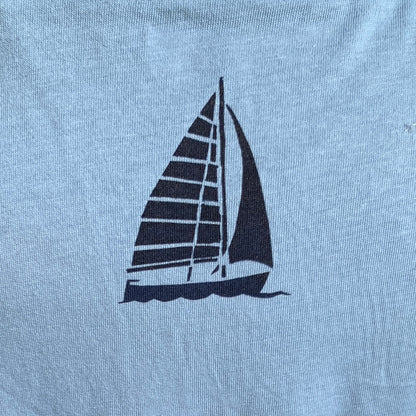 Detail of pale blue T-shirt with turquoise blue design  of boat on back.