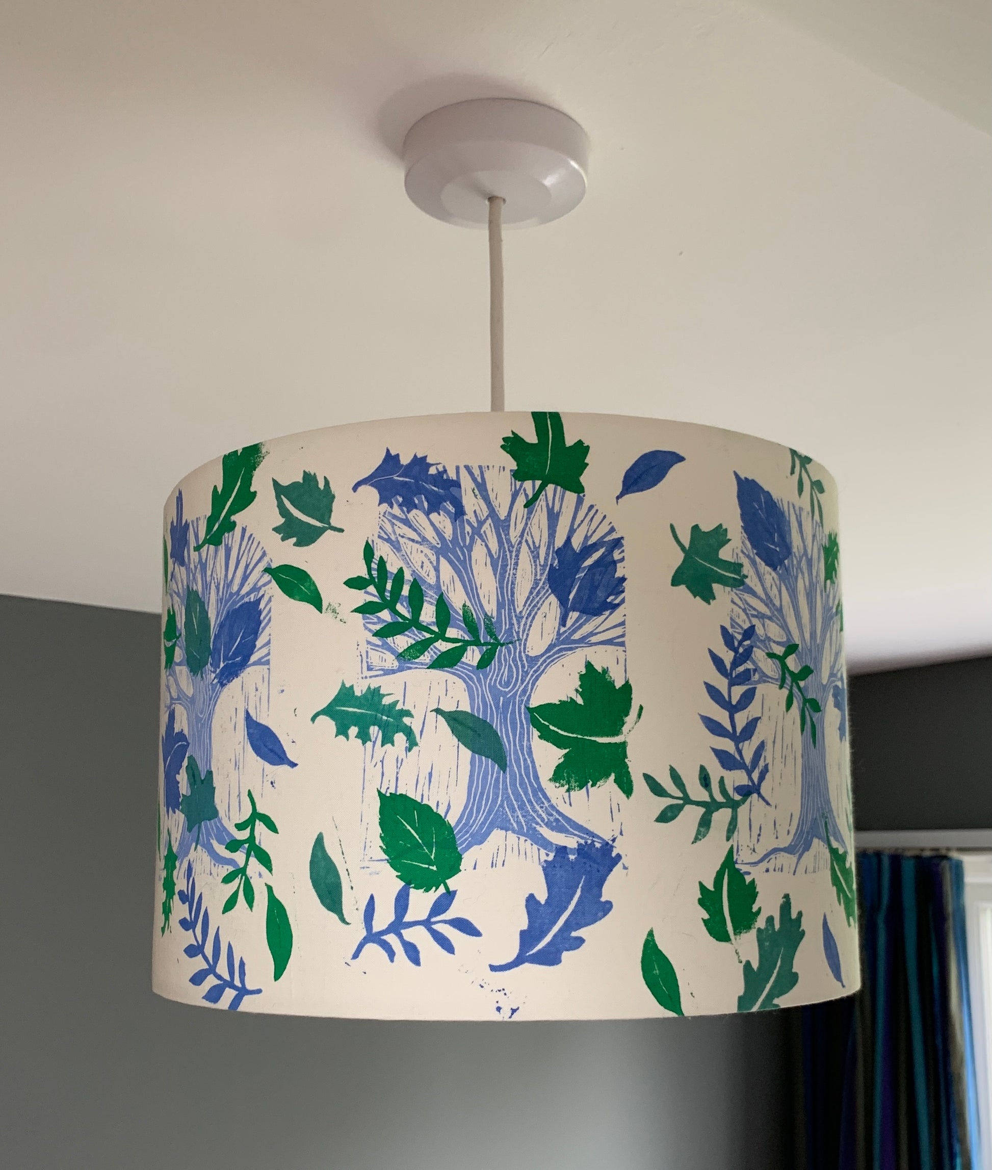 Blue and green handprinted lampshade featuring trees and leaves.