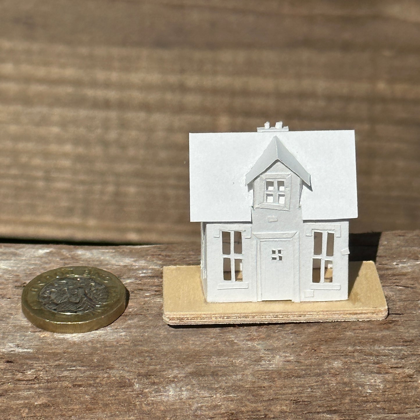  Miniature handmade paper house next to coin for scale