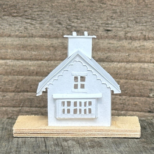 white paper gable fronted house with double chimney on plywood base 