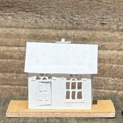 white paper house with arched windows on plywood base