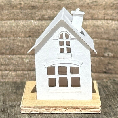 white paper house with arched windows on plywood base