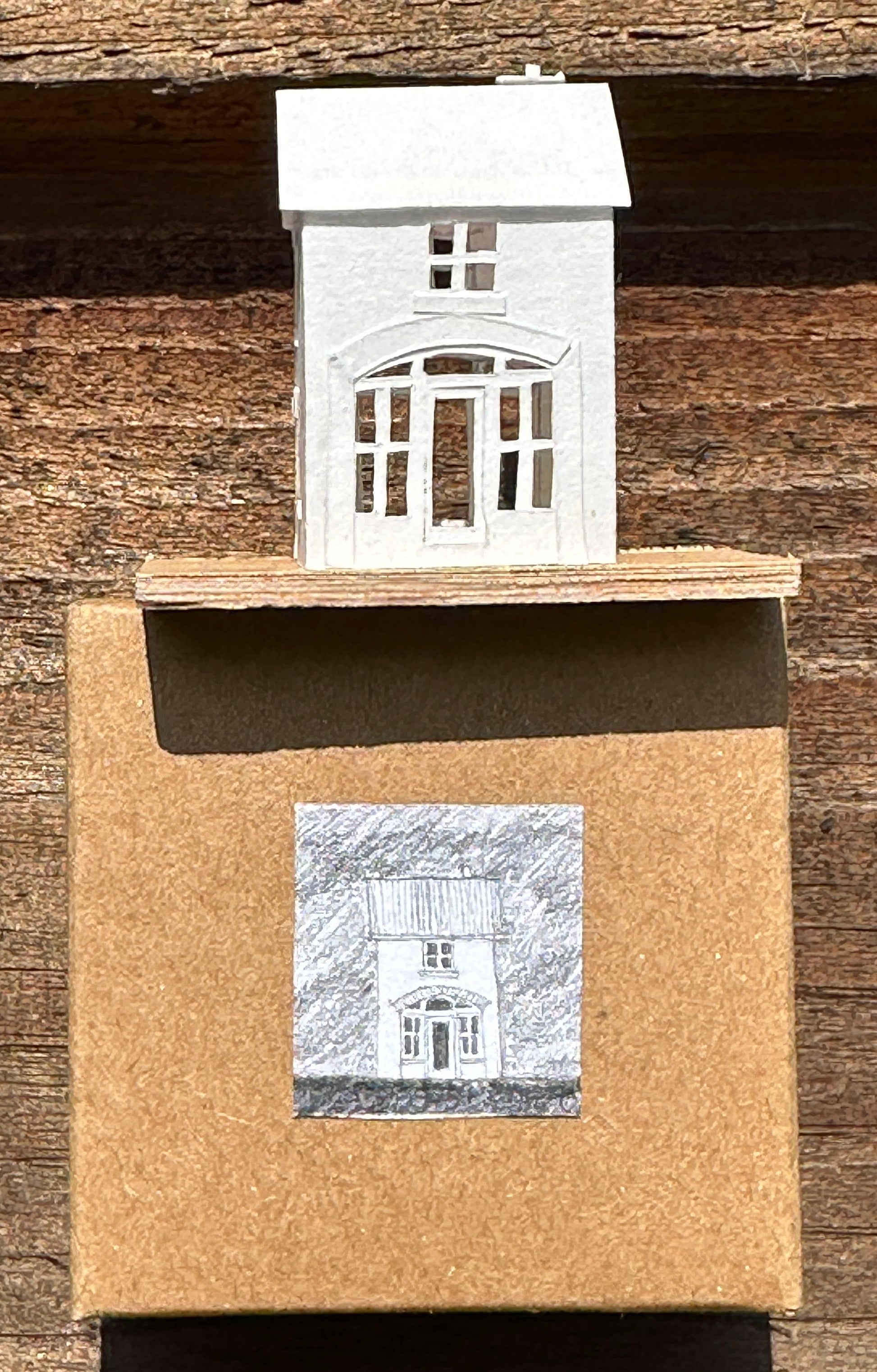 white paper coach house on plywood base above presentation box