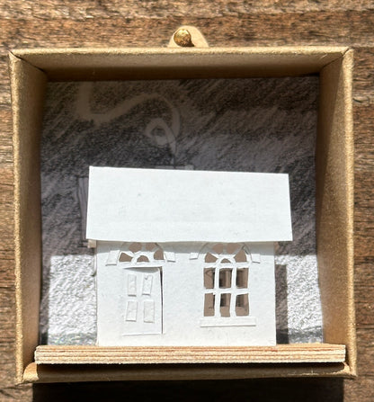white paper house with arched windows on plywood base
