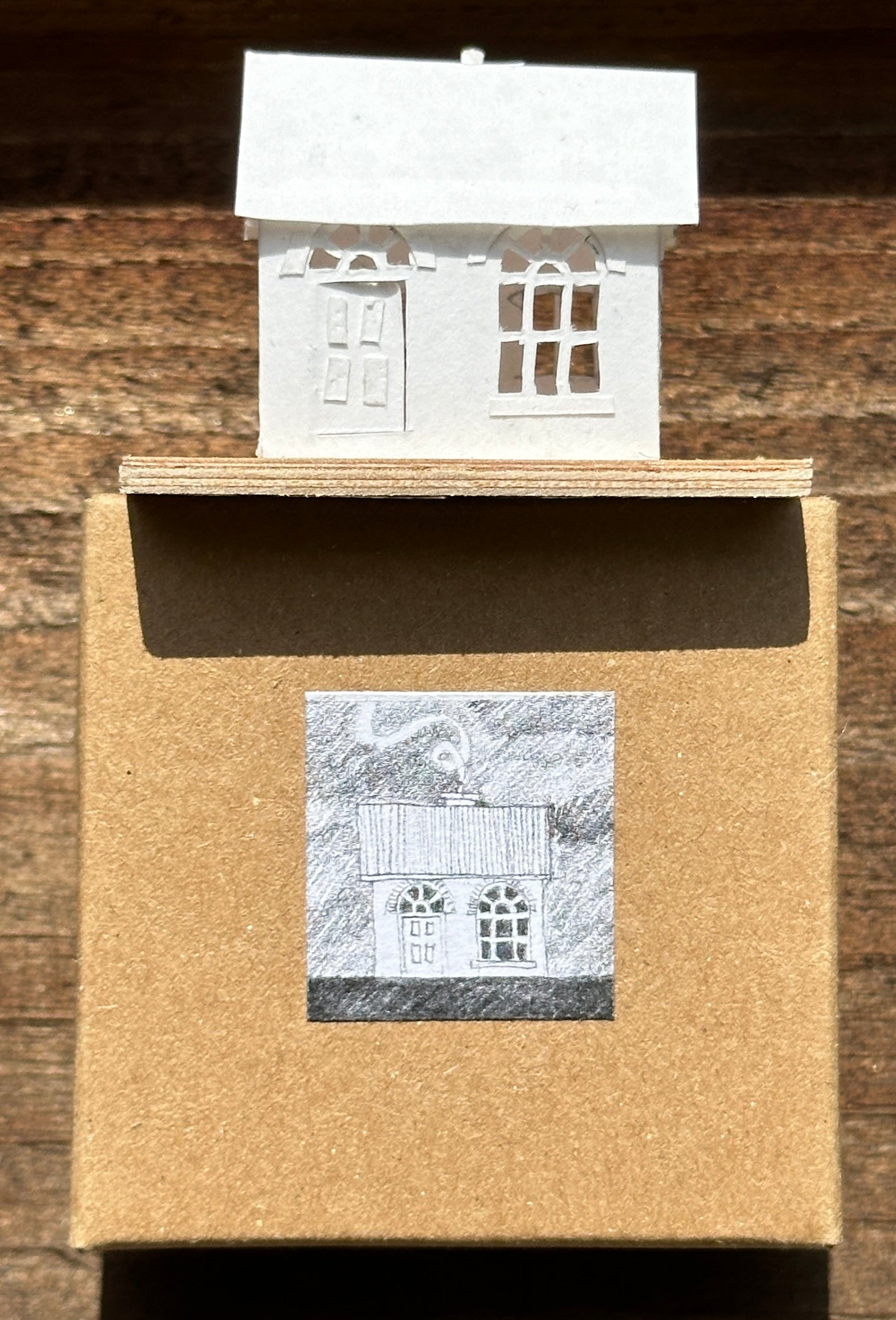 white paper house with arched windows on plywood base